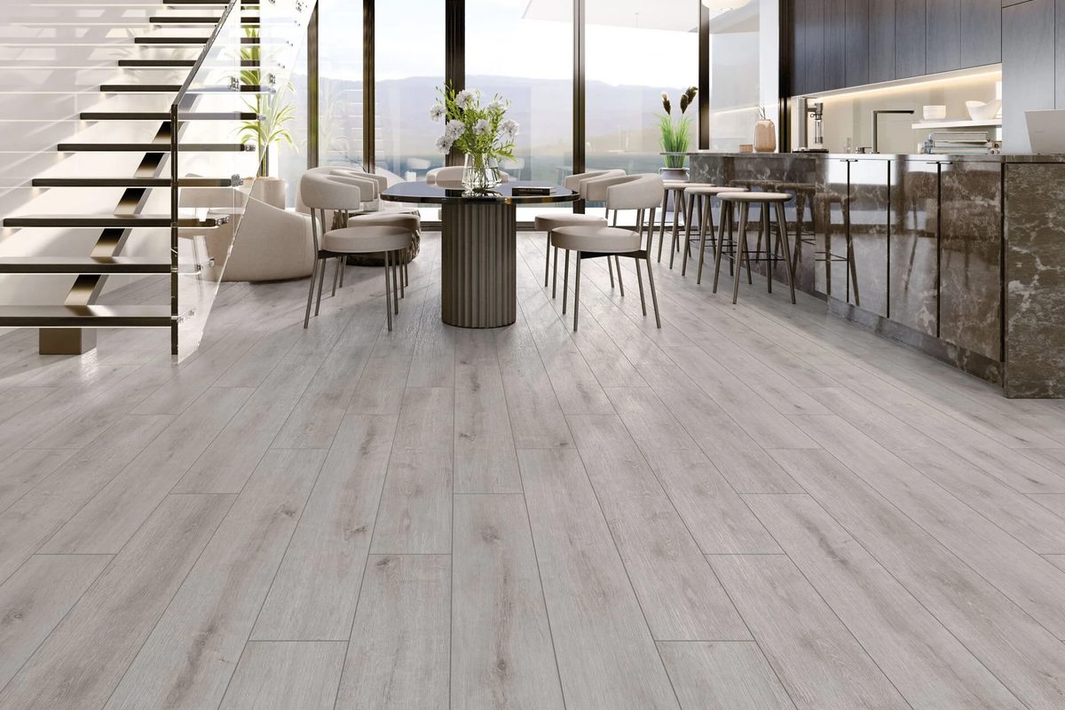 Açık mutfaklı geniş bir salonda gri tonlu laminat parke; geniş alanlarda 10 mm daha tok bir his verir